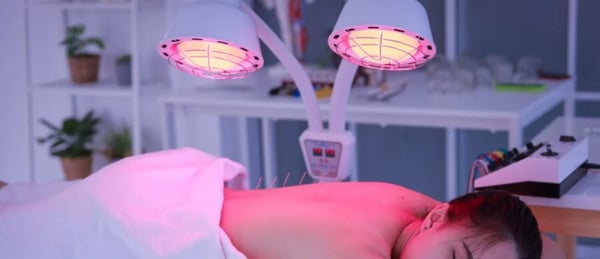 Woman receiving acupuncture under infrared heat lamps