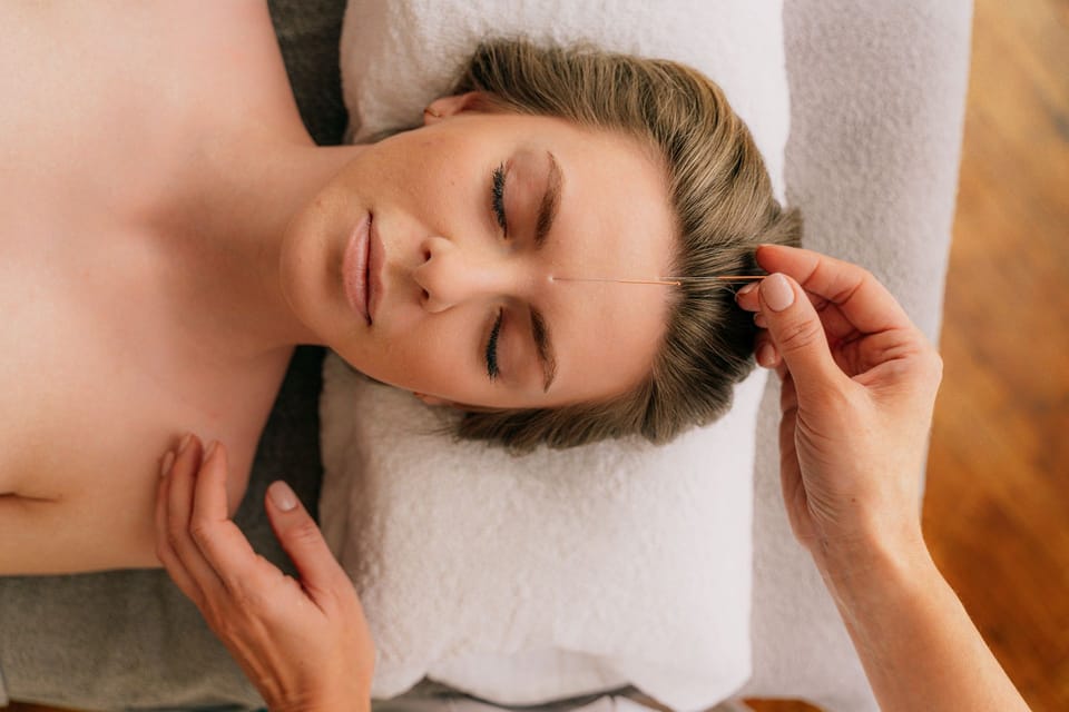 Woman relaxing with eyes closed during a facial acupuncture treatment